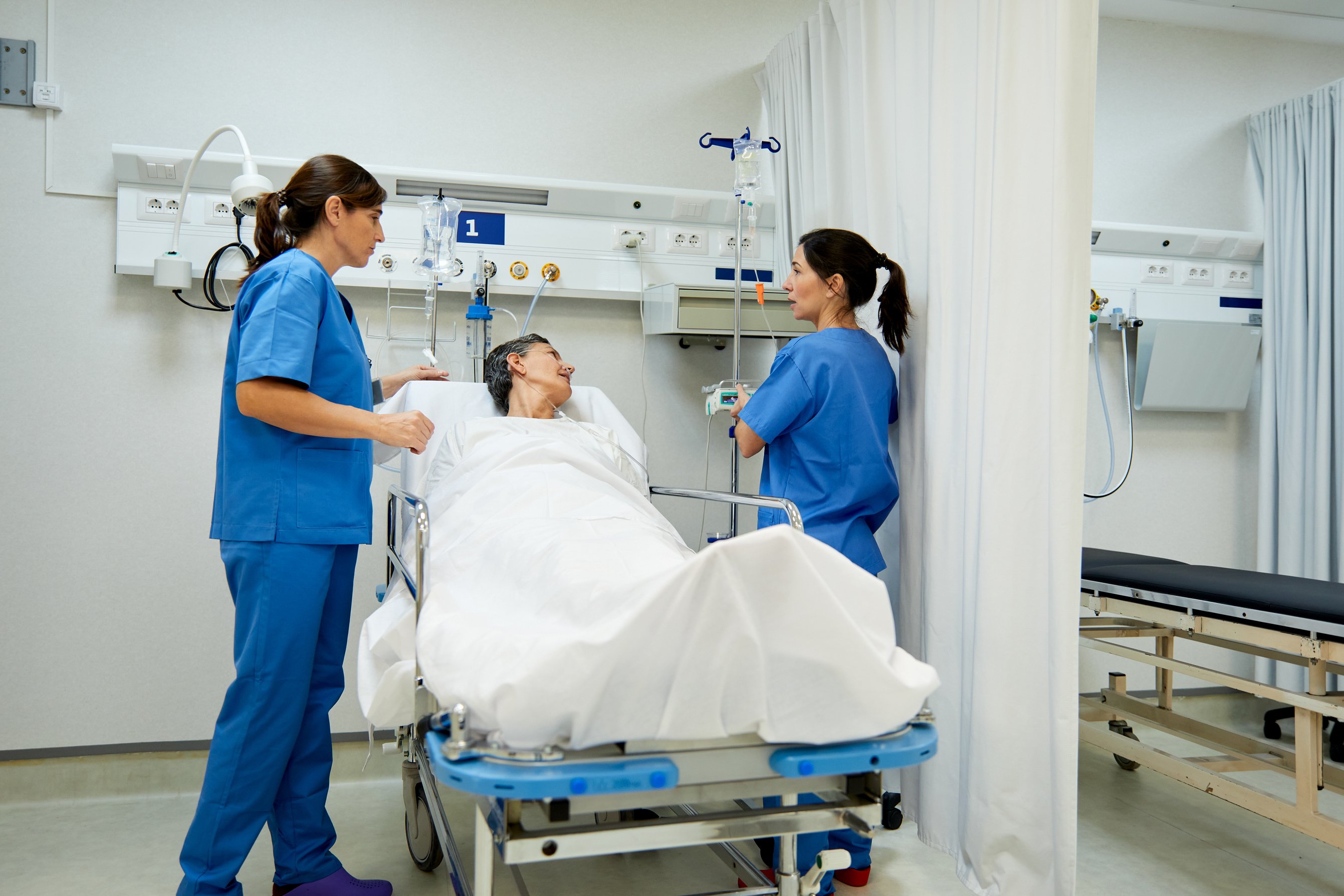Two nurses take care of a patient in the post operative room.